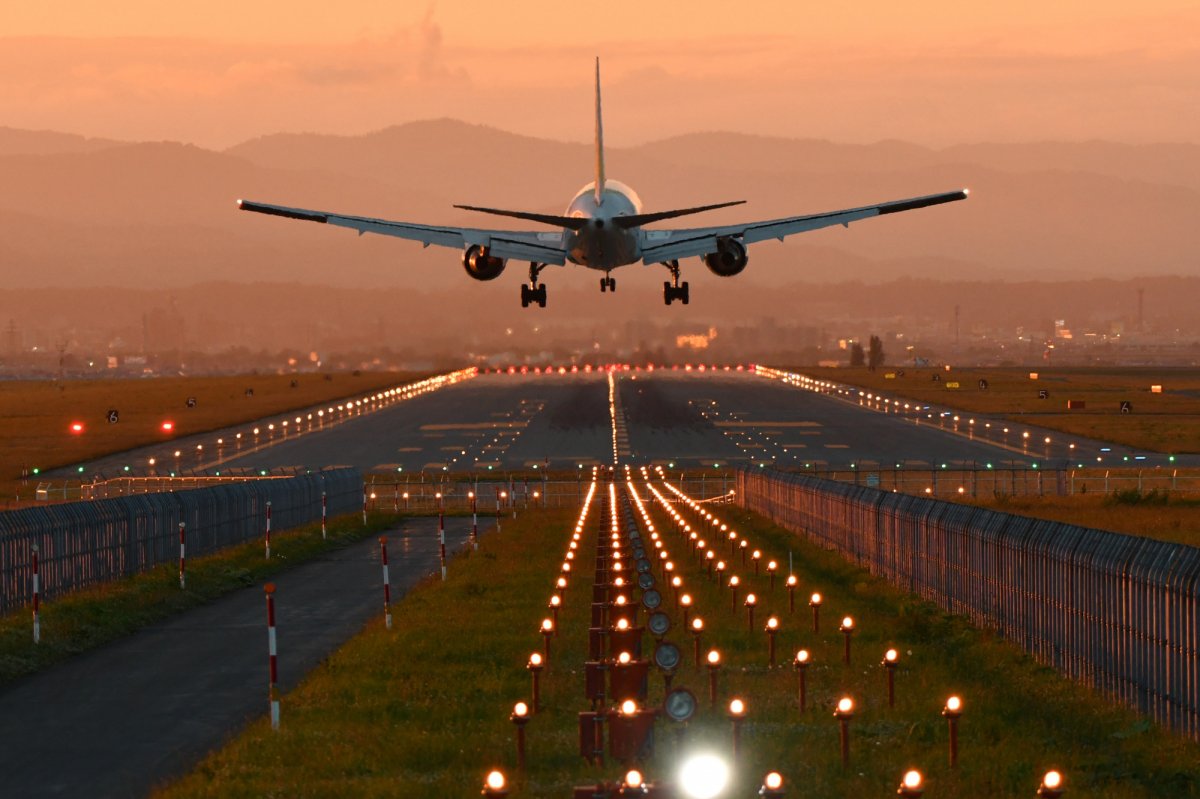 An airplane landing on a lit runway against a hazy background