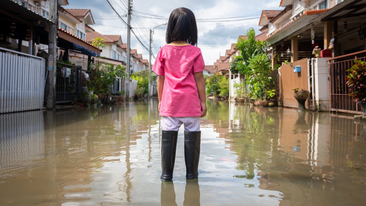 A young girl stands in floodwaters in a street