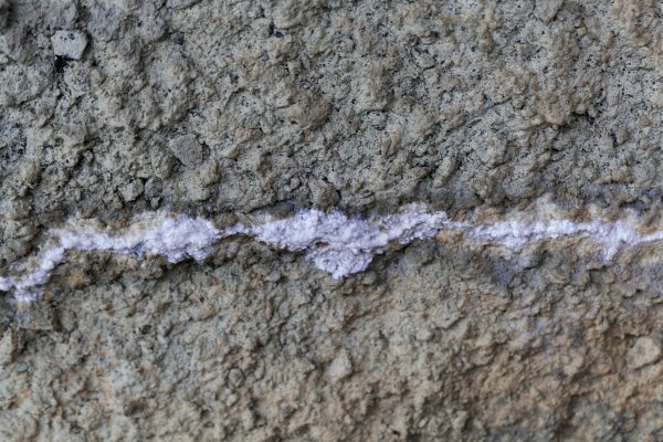 Concrete with a fracture and white carbonate crystallization