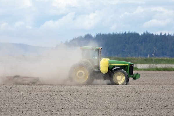 A tractor kicks up dust in a field