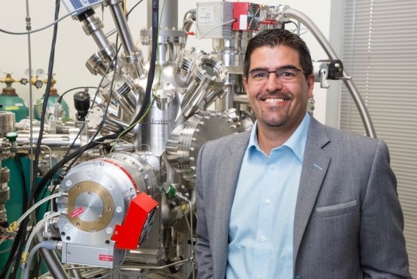 A man stands in front of a laboratory machine used in nuclear engineering research.  