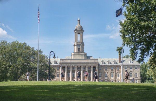 Sunny day outside of Old Main with students walking by