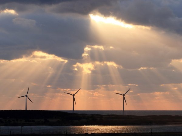 Wind turbines with sunbeams breaking through clouds in the background