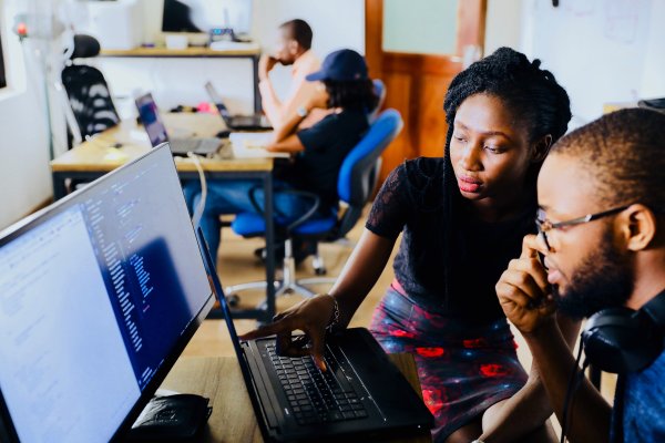 African woman working with african man on computer in a office setting