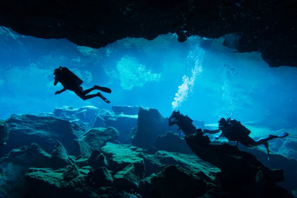 Cave divers swimming in a an underwater cave