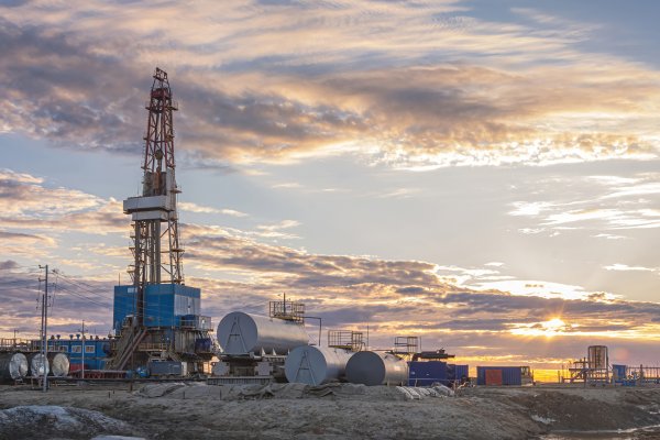 Infrastructure and equipment for drilling wells and oil and gas production. In the background there is a beautiful sky in the rays of the setting sun