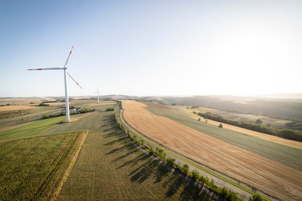 Wind power turbines stand in agricultural fields