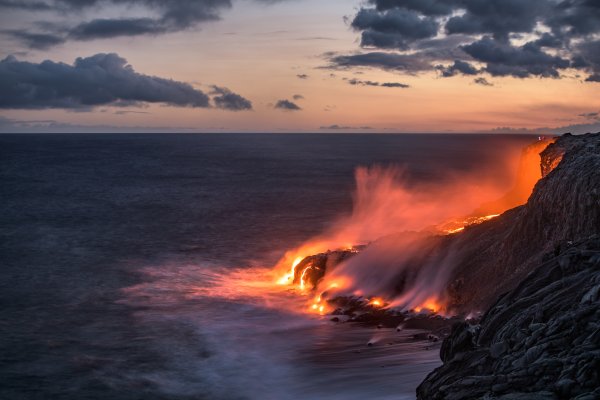 Lava pours into the ocean creating steam at sunset