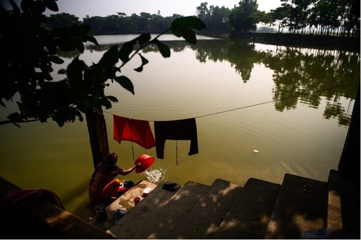 woman doing laundry in body of water