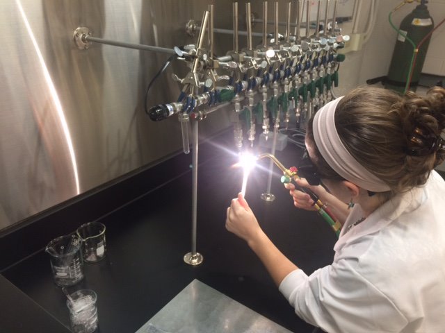 A quartz tube containing a solid sample being sealed under vacuum in the radiocarbon prep lab