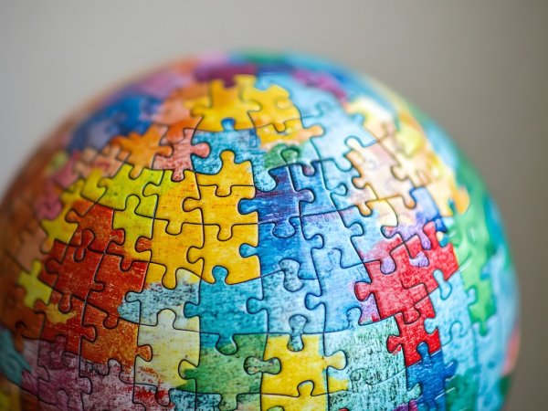 A globe made up of colorful puzzle pieces, each piece representing a different nation or community working together to form a whole