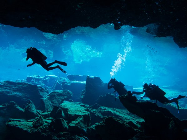 Cave divers swimming in a an underwater cave