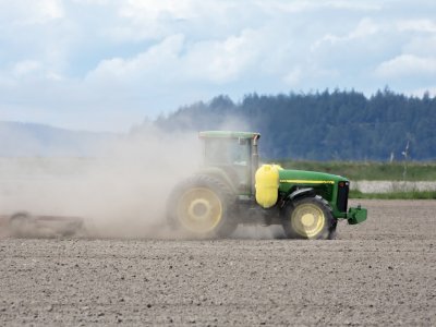 A tractor kicks up dust in a field