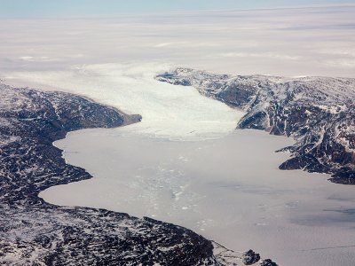 A glacier draining from the Greenland ice sheet flows into a sea ice and iceberg-filled fjord. (credit: Luke Trusel)