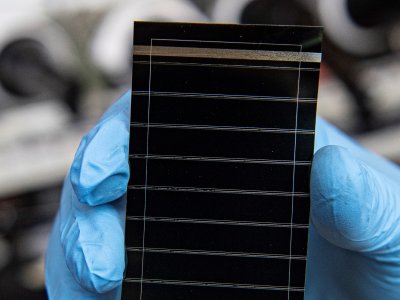 A gloved hand holds a perovskite solar cell