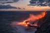 Lava pours into the ocean creating steam at sunset